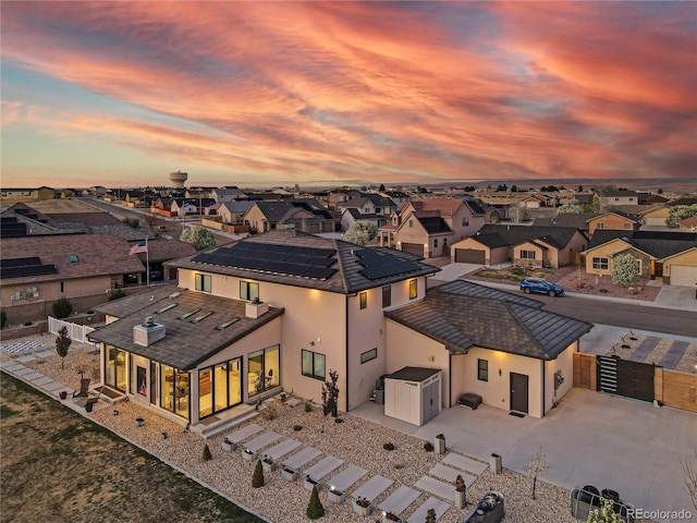 rear view of property with a residential view, a fenced backyard, a gate, solar panels, and driveway