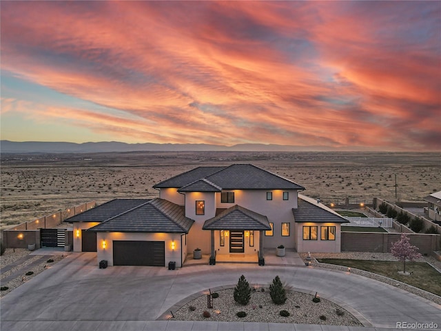 view of front of home featuring a tile roof, a mountain view, fence, a garage, and curved driveway