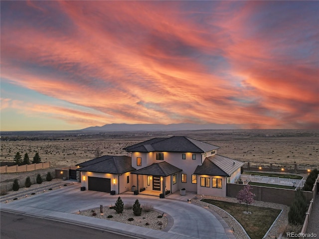 view of front of house featuring a mountain view, fence, an attached garage, curved driveway, and stucco siding