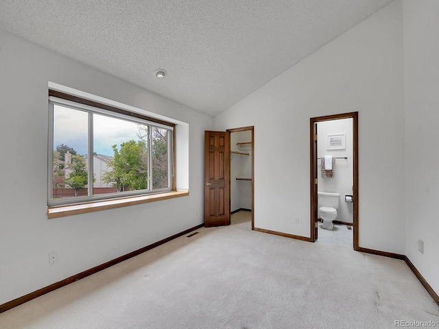 12658 W 1st Pl Unit 78, Denver, CO 80228 - unfurnished bedroom featuring light carpet, a textured ceiling, a walk in closet, vaulted ceiling, and connected bathroom