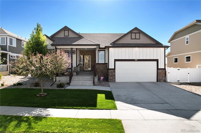 1210 Muskox St, Severance, CO 80550 - view of front of home with driveway, an attached garage, a gate, stone siding, and a shingled roof