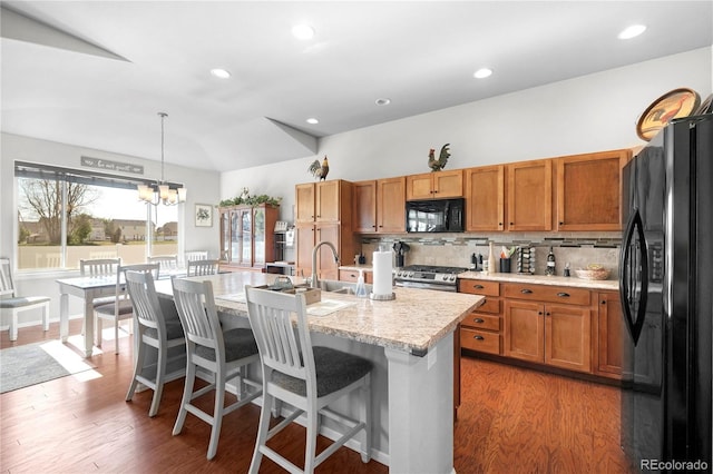 1210 Muskox St, Severance, CO 80550 - kitchen with black appliances, a chandelier, tasteful backsplash, a kitchen breakfast bar, and an island with sink
