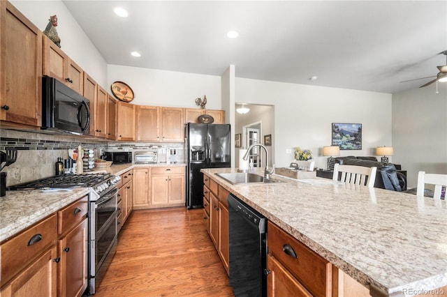 1210 Muskox St, Severance, CO 80550 - kitchen with black appliances, light countertops, open floor plan, ceiling fan, and a center island with sink