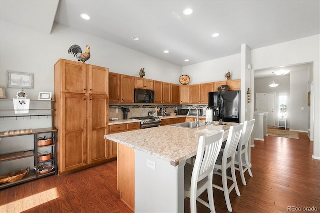 1210 Muskox St, Severance, CO 80550 - kitchen with black appliances, light countertops, an island with sink, dark wood-style floors, and recessed lighting