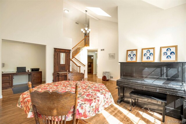 801 S 15th Ave, Brighton, CO 80601 - dining space featuring stairs, a skylight, wood finished floors, a chandelier, and high vaulted ceiling