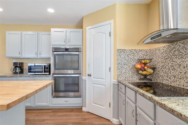 801 S 15th Ave, Brighton, CO 80601 - kitchen with island range hood, stainless steel appliances, wooden counters, light wood-style floors, and tasteful backsplash