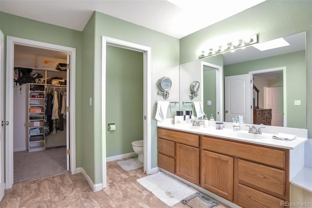 801 S 15th Ave, Brighton, CO 80601 - bathroom with vanity, toilet, a walk in closet, a skylight, and baseboards