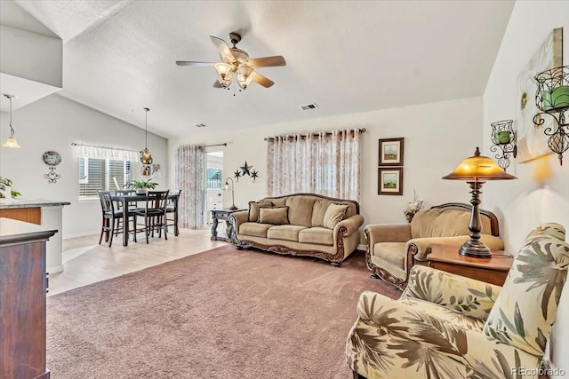 carpeted living room with ceiling fan and vaulted ceiling