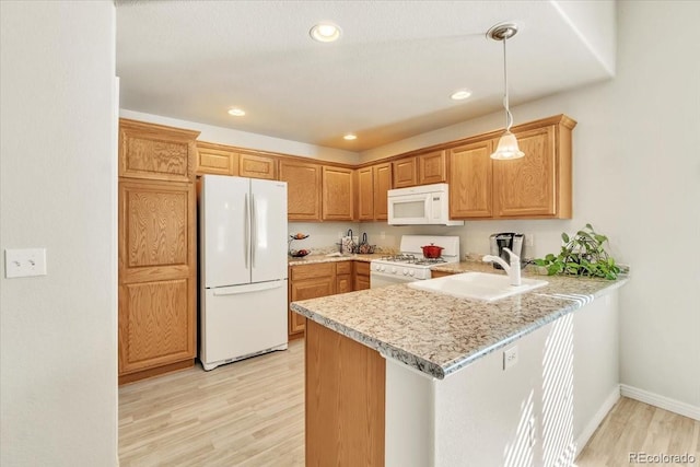 kitchen with pendant lighting, white appliances, sink, kitchen peninsula, and light wood-type flooring