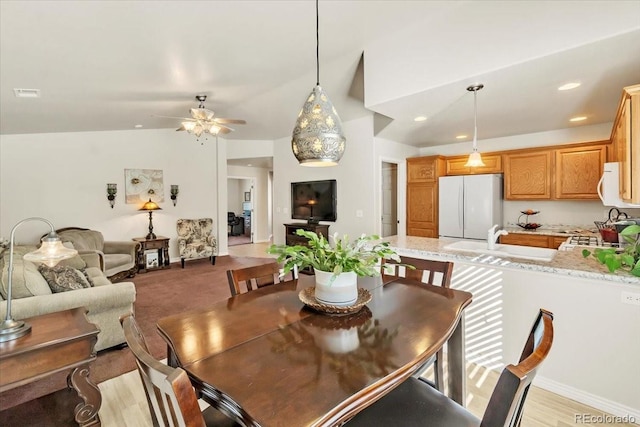 dining area with ceiling fan, light wood-type flooring, and sink