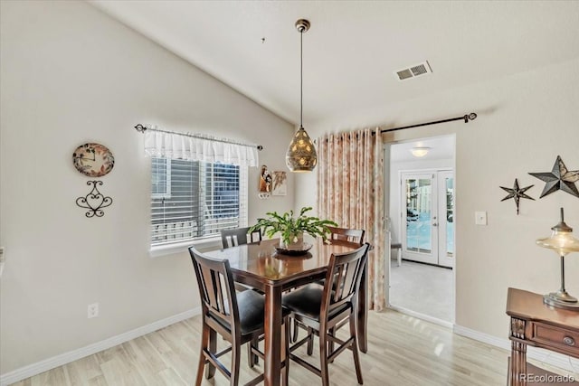 dining area with light hardwood / wood-style flooring, lofted ceiling, and french doors