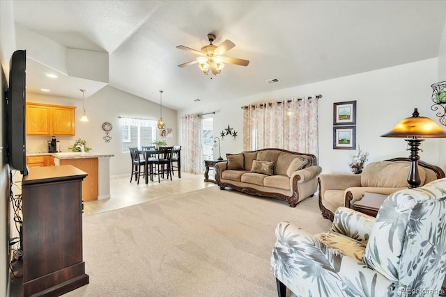 living area with a ceiling fan, light carpet, vaulted ceiling, and visible vents