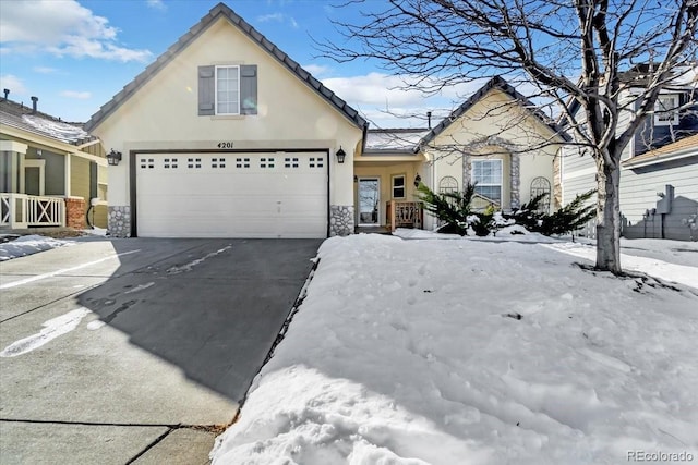 view of front of house with driveway, stone siding, an attached garage, and stucco siding