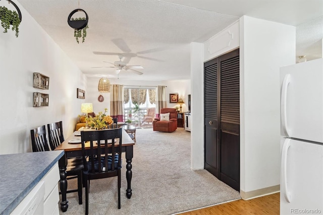 dining area with a textured ceiling, ceiling fan, and light hardwood / wood-style flooring