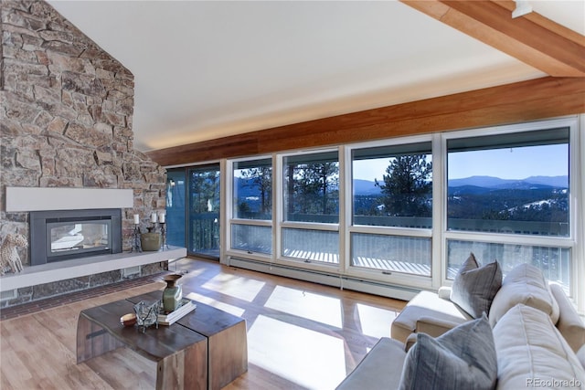 living room featuring vaulted ceiling, baseboard heating, a mountain view, hardwood / wood-style flooring, and a fireplace