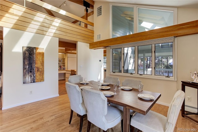 dining room with light hardwood / wood-style floors, a high ceiling, and baseboard heating