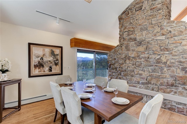 dining area featuring track lighting, a baseboard radiator, and light hardwood / wood-style floors