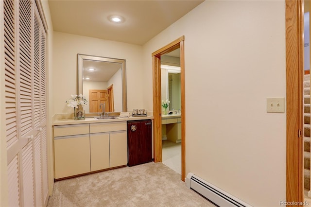 corridor featuring light colored carpet, sink, and a baseboard heating unit