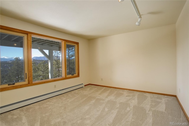 carpeted empty room featuring a mountain view, track lighting, and baseboard heating