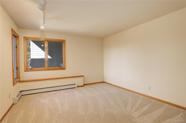 empty room featuring a baseboard radiator, rail lighting, and light colored carpet