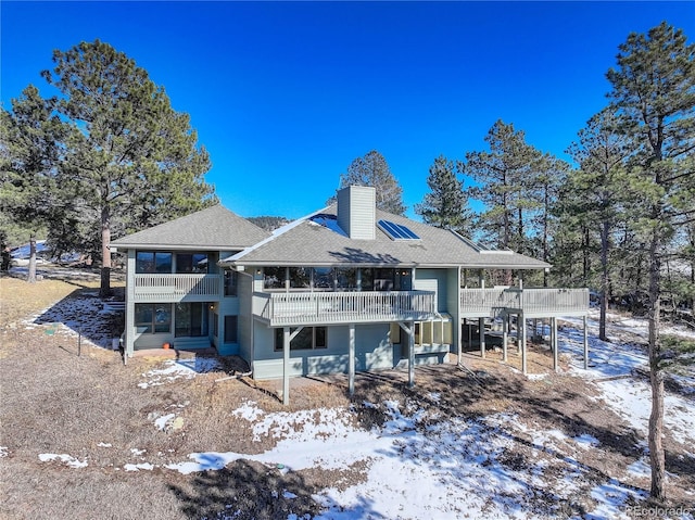 snow covered rear of property featuring a deck