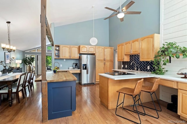 6305 W 6th Ave Unit C12, Lakewood, CO 80214 - kitchen featuring stainless steel fridge with ice dispenser, a peninsula, light brown cabinetry, high vaulted ceiling, and tasteful backsplash