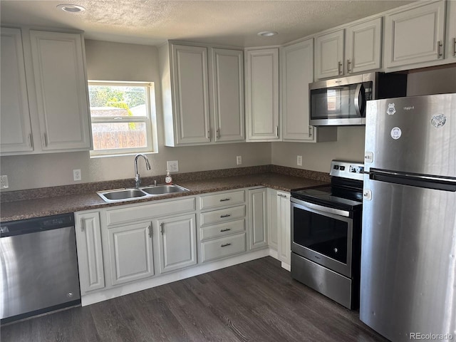 1222 Yosemite St, Denver, CO 80220 - kitchen featuring appliances with stainless steel finishes, dark countertops, dark wood-type flooring, a textured ceiling, and white cabinetry