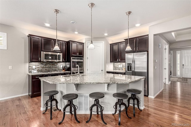 7991 Heritage Dr, Thornton, CO 80602 - kitchen featuring stainless steel appliances, a sink, tasteful backsplash, a kitchen island with sink, and recessed lighting