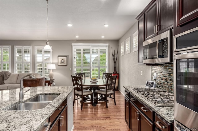 7991 Heritage Dr, Thornton, CO 80602 - kitchen with appliances with stainless steel finishes, a sink, light wood-style floors, recessed lighting, and decorative light fixtures