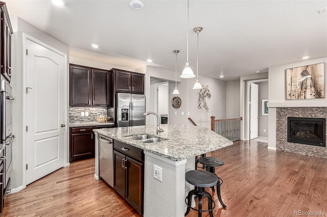 7991 Heritage Dr, Thornton, CO 80602 - kitchen with stainless steel appliances, a sink, a kitchen bar, light wood finished floors, and recessed lighting