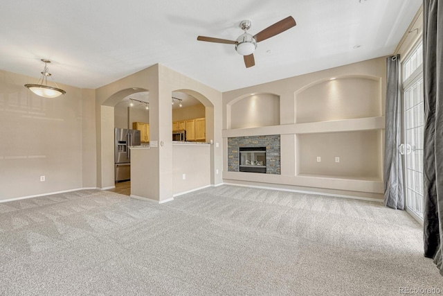 12711 Colorado Blvd Unit 714G, Thornton, CO 80241 - unfurnished living room featuring a ceiling fan, light colored carpet, baseboards, and a stone fireplace