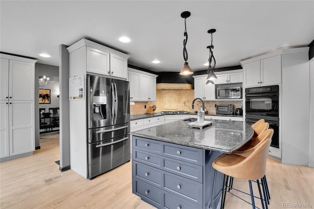 kitchen featuring visible vents, light wood finished floors, white cabinets, and stainless steel appliances