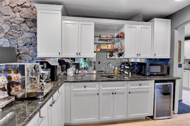 kitchen with wine cooler, dark stone counters, white cabinets, and black microwave