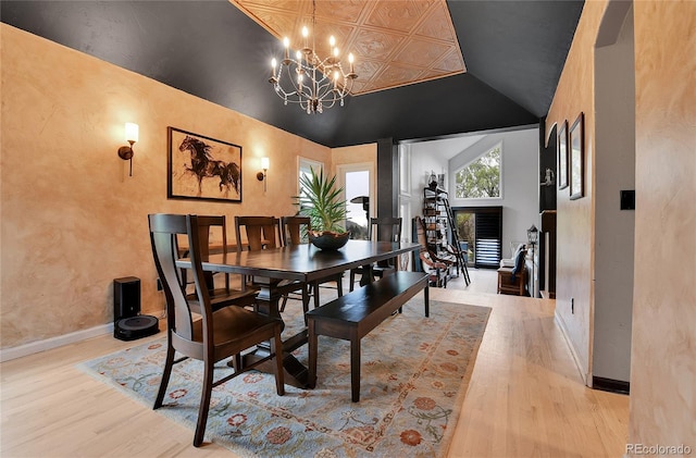 dining space with light wood-style floors, baseboards, lofted ceiling, and a chandelier
