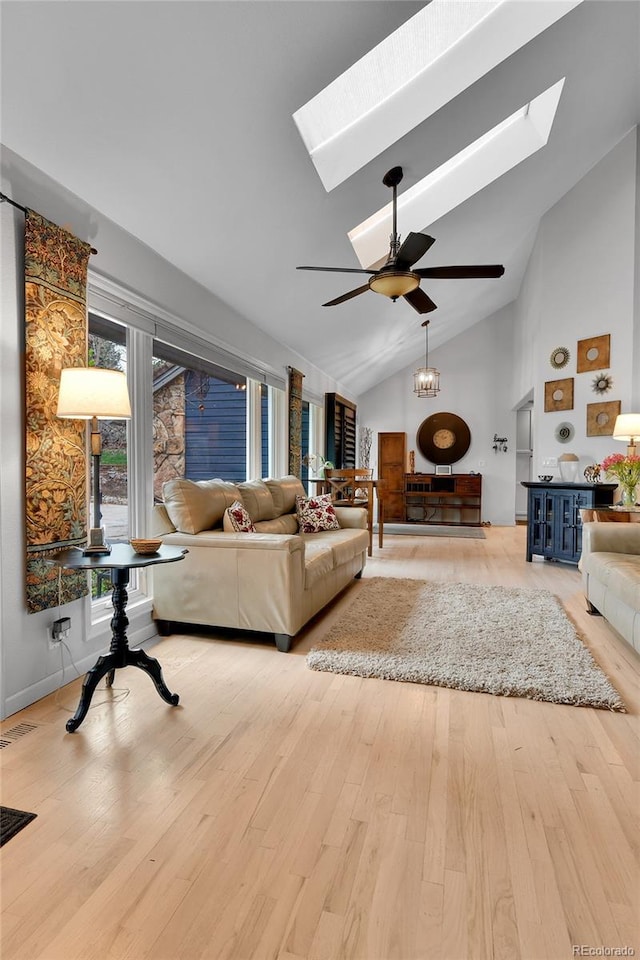 living room featuring a skylight, ceiling fan, high vaulted ceiling, and wood finished floors