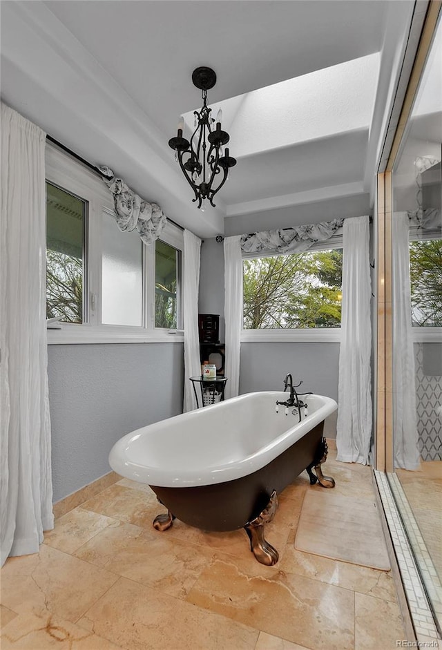 full bath featuring a healthy amount of sunlight, a freestanding tub, and stone tile floors
