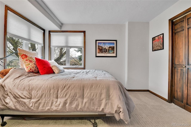 bedroom featuring baseboards, a textured ceiling, and light carpet