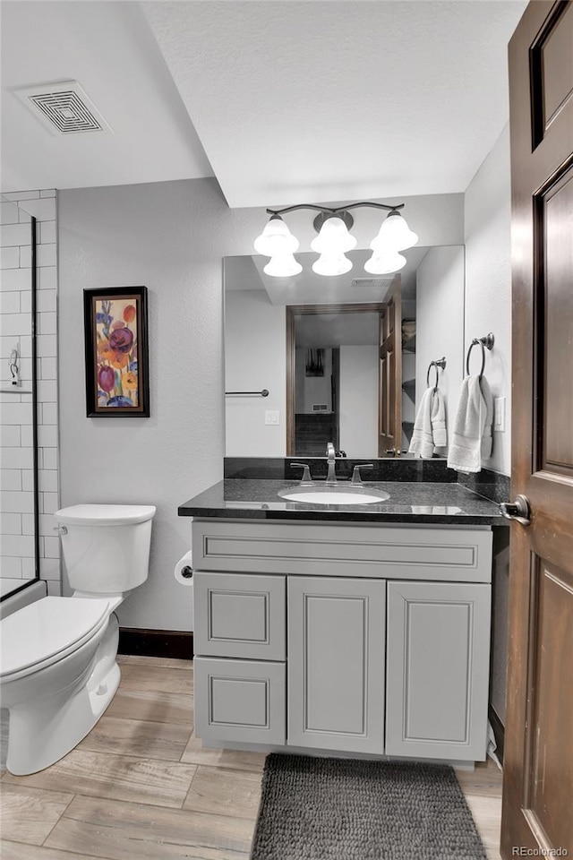 bathroom with visible vents, vanity, wood finished floors, toilet, and baseboards