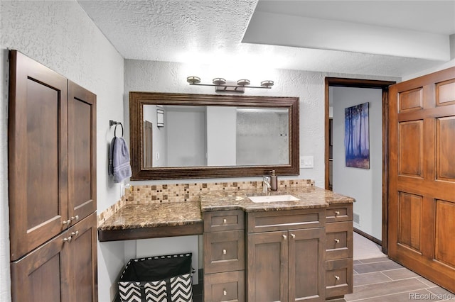 bathroom featuring vanity, a textured ceiling, and a textured wall