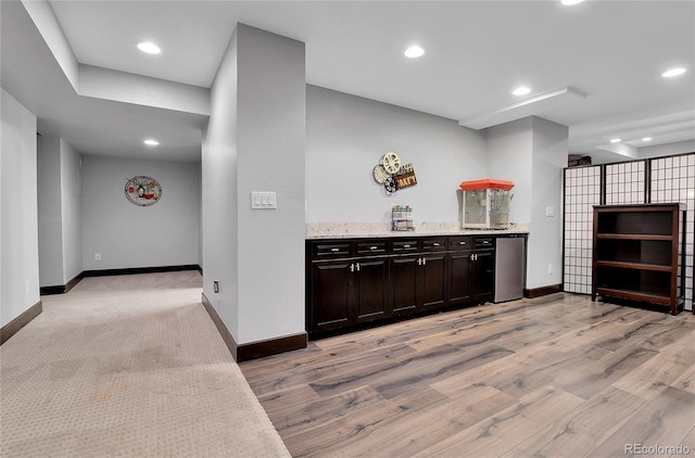 kitchen with baseboards, recessed lighting, light wood-style flooring, and light stone countertops