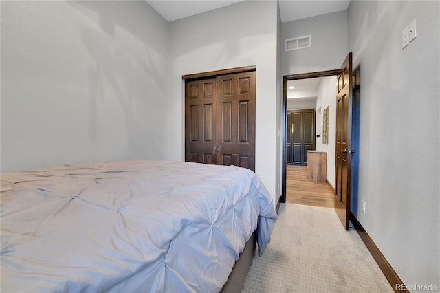 bedroom featuring visible vents, baseboards, a closet, and light carpet