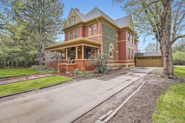 victorian-style house with a porch, brick siding, an outbuilding, and a front lawn