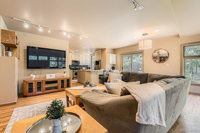 living room with track lighting, light wood-style flooring, recessed lighting, and baseboards