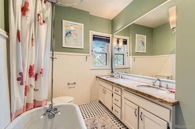 full bath with a wainscoted wall, a tub, double vanity, toilet, and a shower with curtain