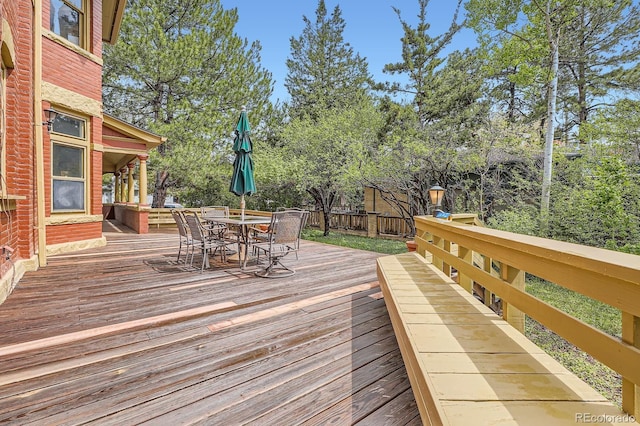 wooden terrace featuring outdoor dining space and a fenced backyard
