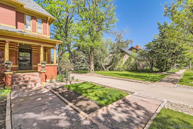 view of property exterior with brick siding, a porch, and a lawn