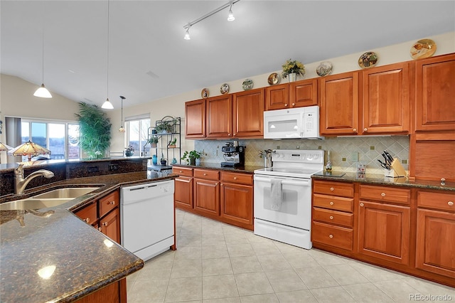 kitchen with pendant lighting, lofted ceiling, a sink, dark stone counters, and white appliances