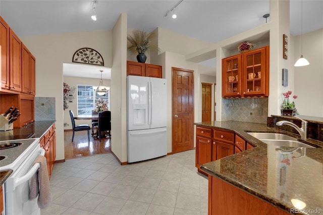 kitchen featuring hanging light fixtures, glass insert cabinets, a sink, vaulted ceiling, and white appliances