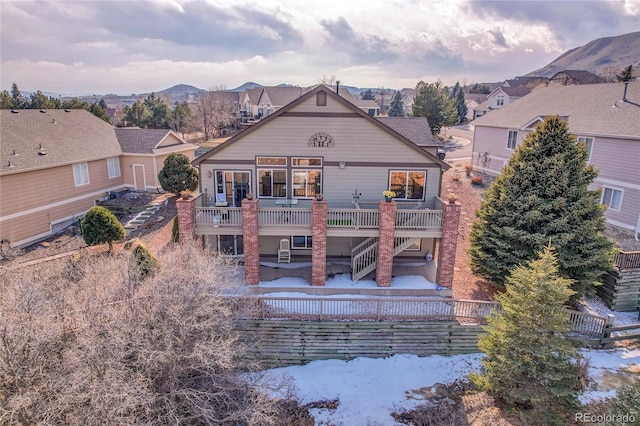 back of property with stairs, a deck with mountain view, and a residential view