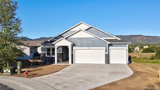 view of front of house with board and batten siding, a mountain view, fence, a garage, and driveway